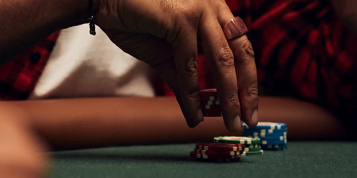 Mão alcançando fichas — representando um movimento agressivo de 3-bet em um jogo de cash.