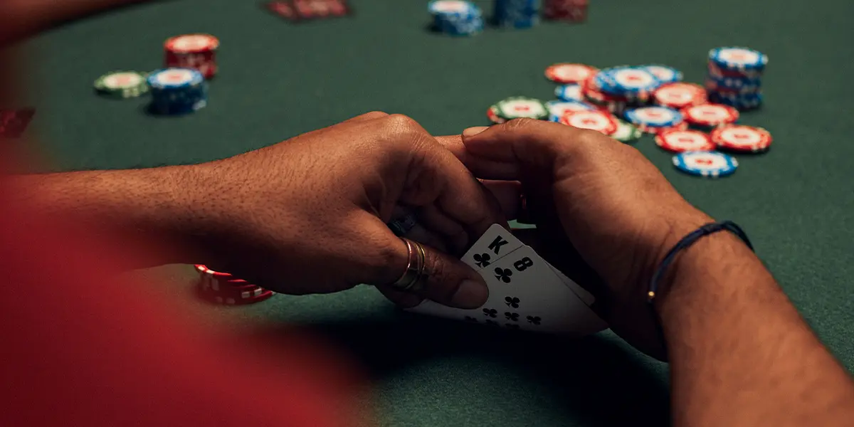 Jogador de poker avaliando uma mão de Rei e Oito do mesmo naipe para a sobrevivência.