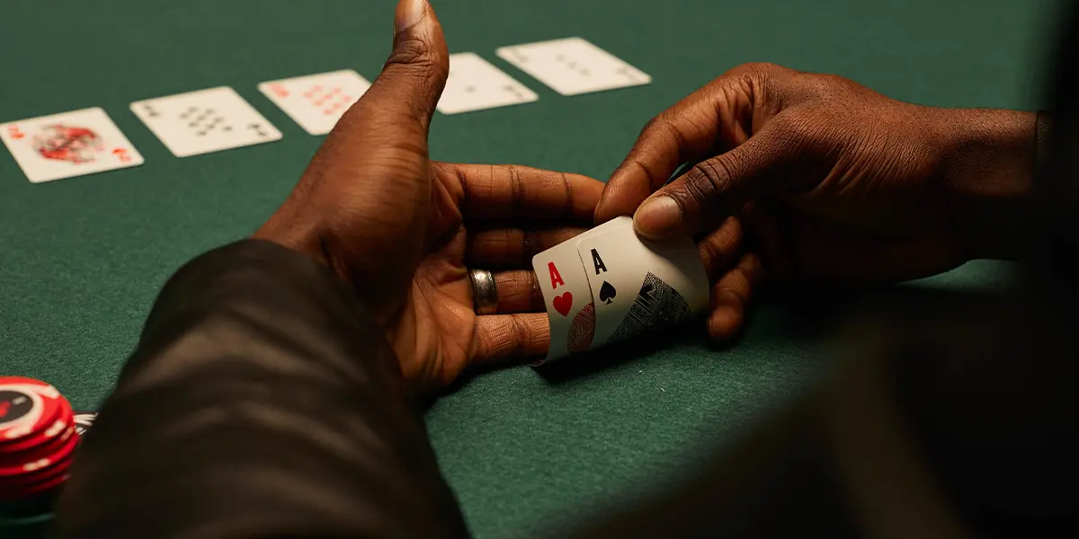 Jogador de poker olhando para o par de ases, a melhor mão inicial absoluta no Texas Hold’em.